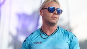 Skolim w niebieskim stroju sportowym i okularach przeciwsłonecznych, na tle sceny.