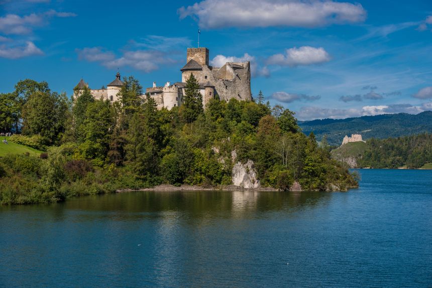 Zamek w Pieninach, otoczony zielenią, nad rzeką, z fotogeniczną scenerią w tle.