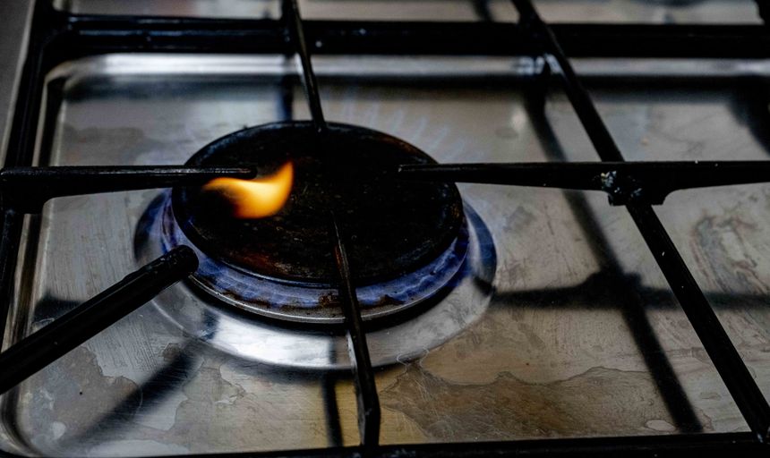 Płomień z palnika gazowego na metalowej kuchence. Cienki dym unosi się wokół.