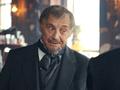 Mężczyzna w eleganckim stroju, z zamyśloną miną, w barze.