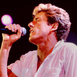 Roger Daltrey z The Who. Mężczyzna z mikrofonem śpiewa, zamknięte oczy, intensywne oświetlenie w tle.