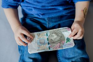 Dziecko trzyma banknot 500 złotych, ubrania w niebieską bluzkę i niebieskie spodnie.