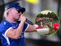 Skolim z mikrofonem na scenie, w tle festiwal z tłumem i kolorowymi namiotami.