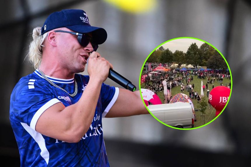 Skolim z mikrofonem na scenie, w tle festiwal z tłumem i kolorowymi namiotami.