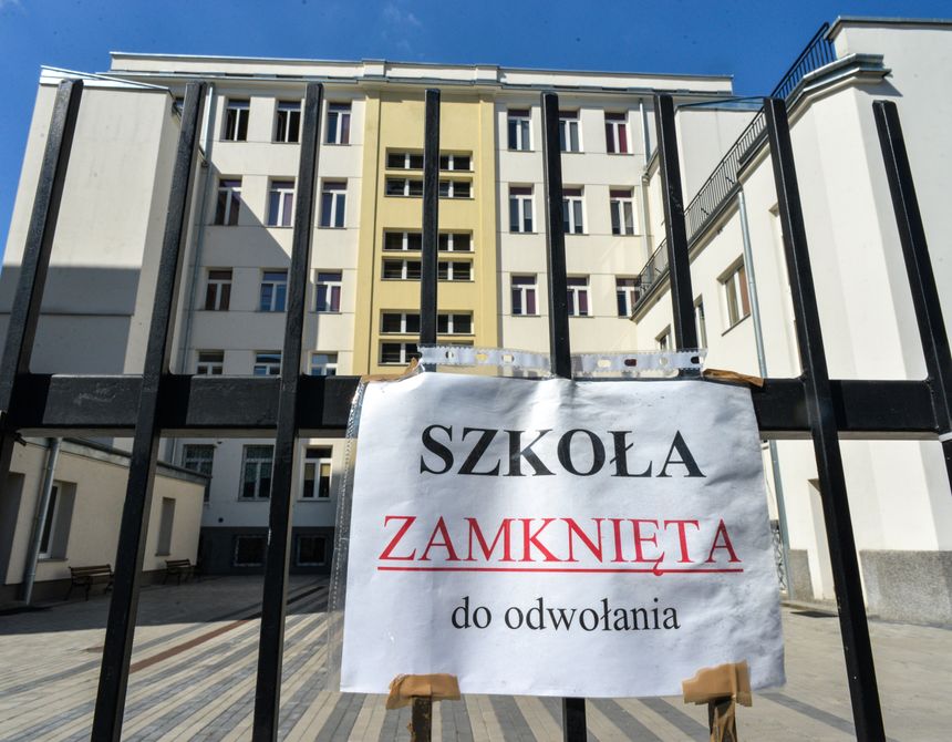 Na zdjęciu widoczna jest zamknięta szkoła, z tablicą informującą „SZKOŁA ZAMKNIĘTA do odwołania”.