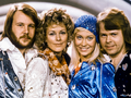 Cztery osoby w stylowych kostiumach lat 70. na tle futurystycznej scenografii.