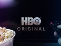 Obrazek przedstawia miskę popcornu obok telewizora z logo HBO Original i pilotem.