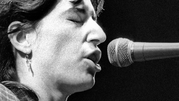 Patti Smith - 1979 rok. Kobieta śpiewa do mikrofonu, zamknięte oczy, skupiona na występie. Czarnobiałe zdjęcie.