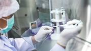 Pracownik laboratorium przygotowuje próbki w zabezpieczonym środowisku.