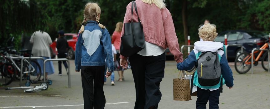 Trzy osoby idące w stronę parkingu: matka z dwójką dzieci, jedno w sercu na kurtce.