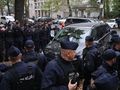 Grupa policjantów w mundurach, zabezpieczająca teren wokół czarnego minivana.