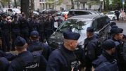 Grupa policjantów w mundurach, zabezpieczająca teren wokół czarnego minivana.
