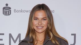 Anna Lewandowska z długimi włosami, uśmiecha się na tle jasnego tła z logo.