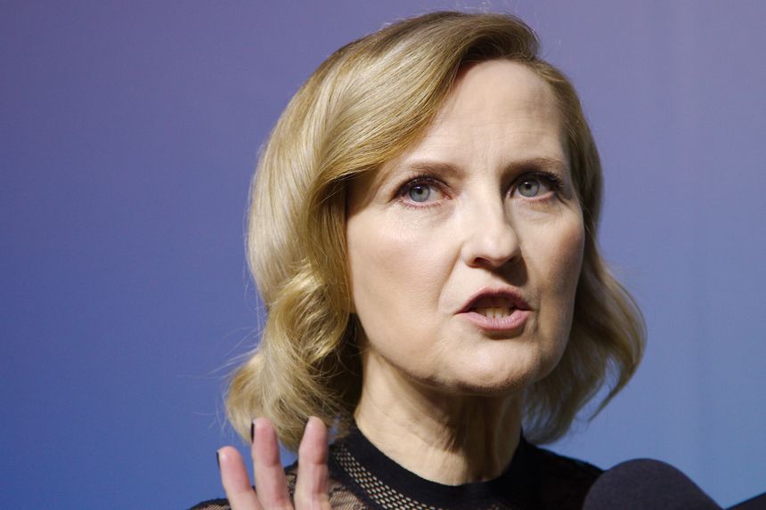 Izabela Kuna z krótkimi, blond włosami, mówi do mikrofonu w eleganckiej bluzce.
