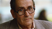 Tadeusz Konwicki w 1985. Mężczyzna w okularach, z lekko zmarszczonym czołem, patrzy z poważnym wyrazem twarzy.