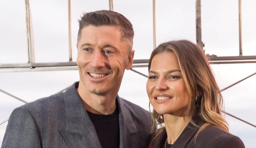 Robert i Anna Lewandowscy pozujący w miejskim krajobrazie z charakterystyczną siatką w tle.