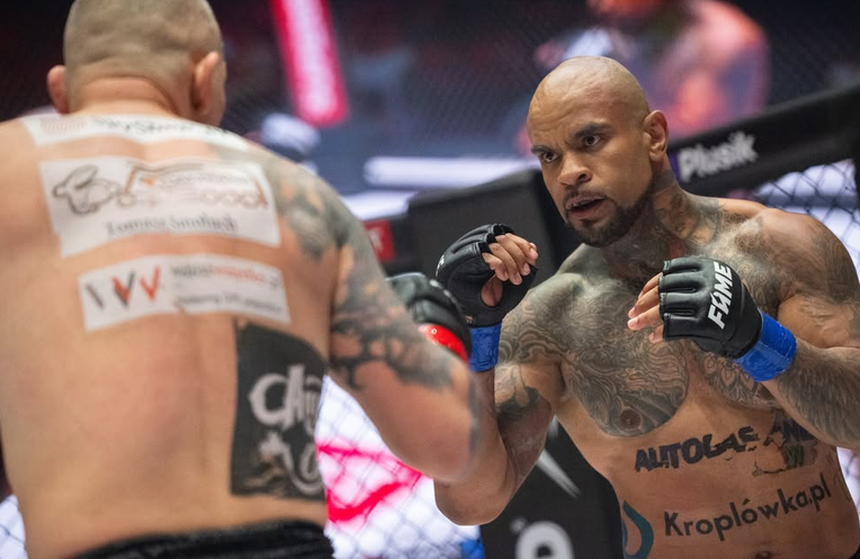 Dwóch zawodników MMA w ringu, skupionych na walce, jeden z nich ma tatuaże.