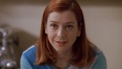 Młoda kobieta z rudymi włosami, uśmiechnięta, w niebieskim swetrze.