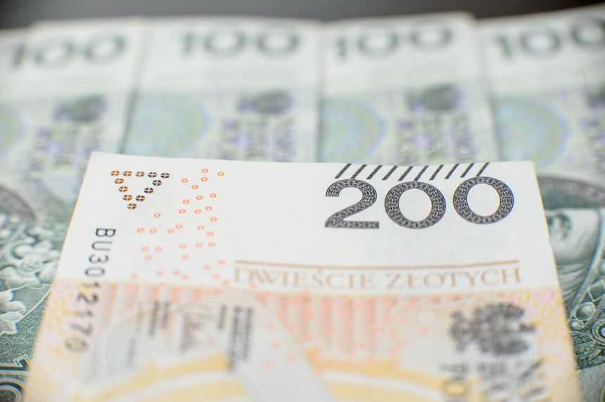 Wizualizacja banknotu 200 złotych, w tle banknoty 100 złotych. Banknot z detalami graficznymi.