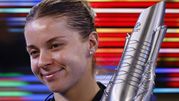 Uśmiechnięta Maja Chwalińska trzyma trofeum, w tle kolorowe pasy światła.