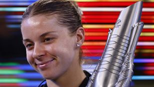 Uśmiechnięta Maja Chwalińska trzyma trofeum, w tle kolorowe pasy światła.
