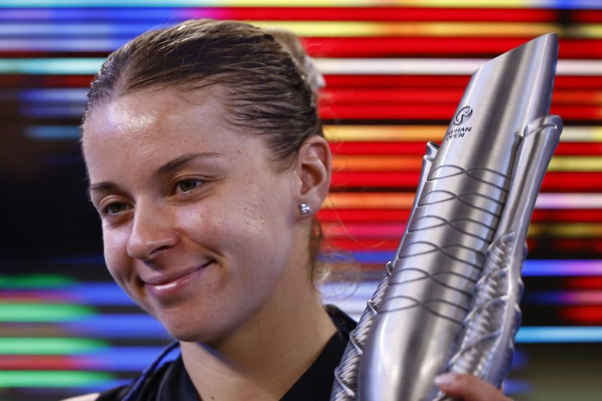 Uśmiechnięta Maja Chwalińska trzyma trofeum, w tle kolorowe pasy światła.