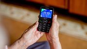 Zdjęcie przedstawia ręce osoby trzymającej telefon komórkowy z wyświetlaczem.