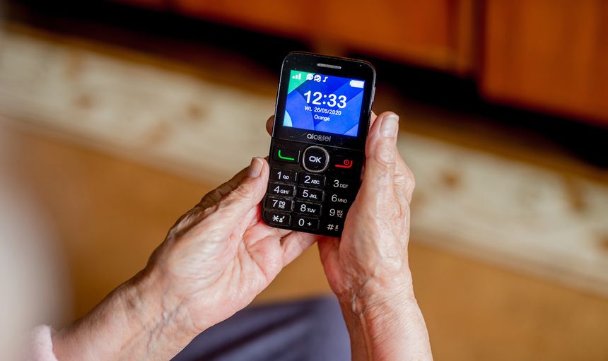 Zdjęcie przedstawia ręce osoby trzymającej telefon komórkowy z wyświetlaczem.