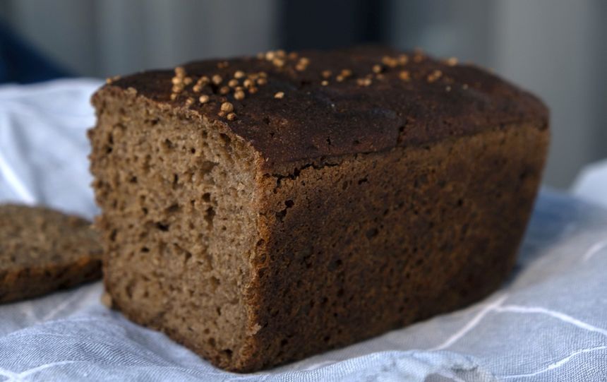 Chleb w ciemnym kolorze z widocznymi otworami, położony na jasnej tkaninie.