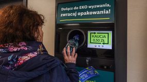 Kobieta wrzuca butelkę do maszyny zwrotnej z napisem o zwrocie kaucji 0,50 zł.