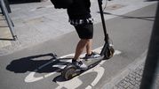 Mężczyzna na hulajnodze elektrycznej porusza się po ścieżce rowerowej w mieście.