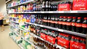 Półka z napojami gazowanymi i sokami, różne marki, w tym Coca-Cola i Pepsi.