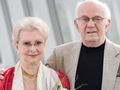 Para starszych ludzi pozująca na zdjęciu, mężczyzna w jasnej marynarce, kobieta z kwiatami.