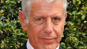 Anthony Bourdain. Mężczyzna z szarymi włosami, uśmiechnięty, w eleganckim ubraniu.