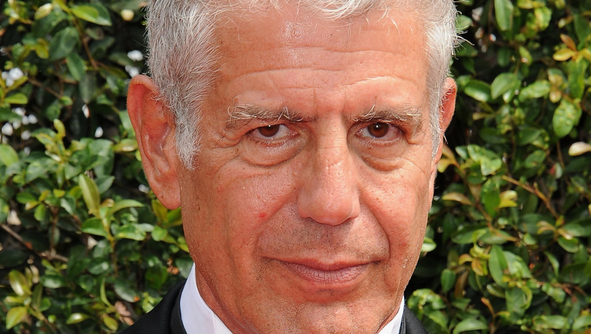 Anthony Bourdain. Mężczyzna z szarymi włosami, uśmiechnięty, w eleganckim ubraniu.
