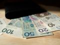 Zestaw polskich banknotów o nominałach 20 zł, 50 zł, 100 zł i 200 zł na tle portfela.