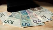 Zestaw polskich banknotów o nominałach 20 zł, 50 zł, 100 zł i 200 zł na tle portfela.