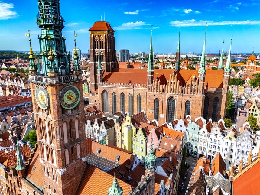 Widok na Gdańsk, z kolorowymi kamienicami i wysokimi wieżami kościołów w tle.