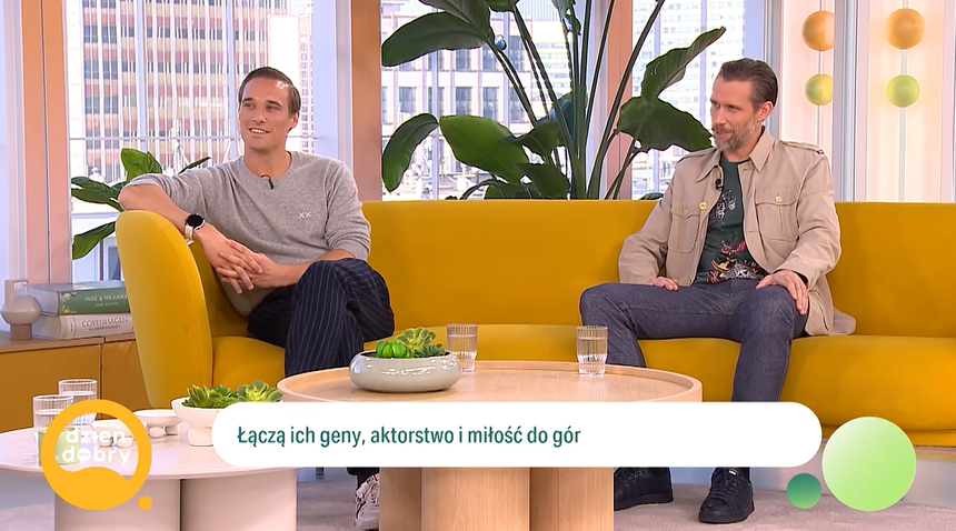 Para mężczyzn na żółtej kanapie, rozmawiają o pasjach i aktorstwie. W tle rośliny i okna.