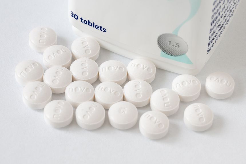 Na zdjęciu widoczna jest biała tabletka obok opakowania z inskrypcją „30 tablets”.