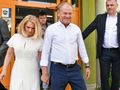 Dwoje ludzi wychodzi z budynku. Mężczyzna w białej koszuli, kobieta w białej sukience.
