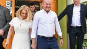 Dwoje ludzi wychodzi z budynku. Mężczyzna w białej koszuli, kobieta w białej sukience.